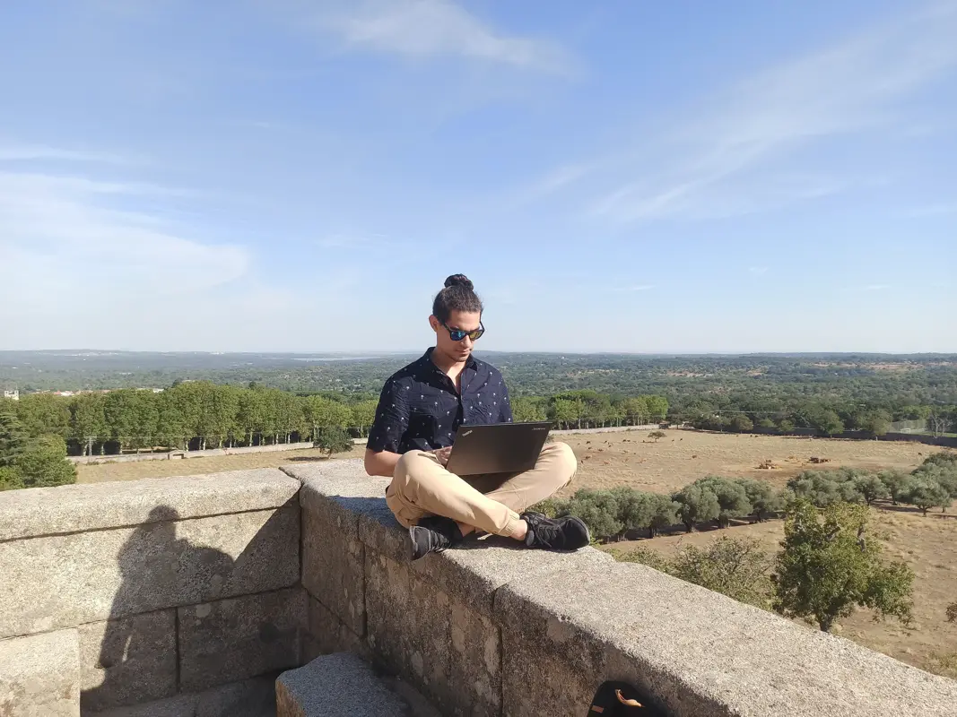 Man working outside, sitting cross legged on a wall