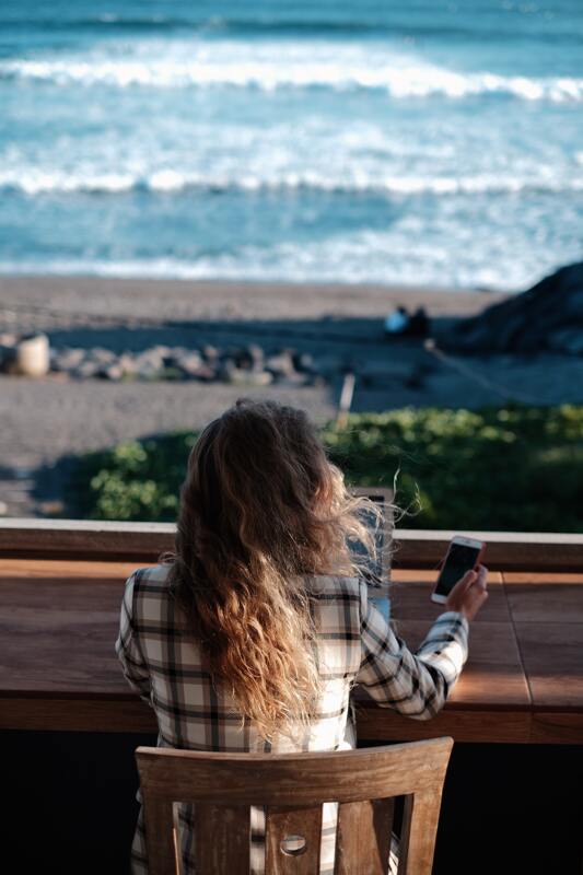 Location independent woman working on her computer by the water